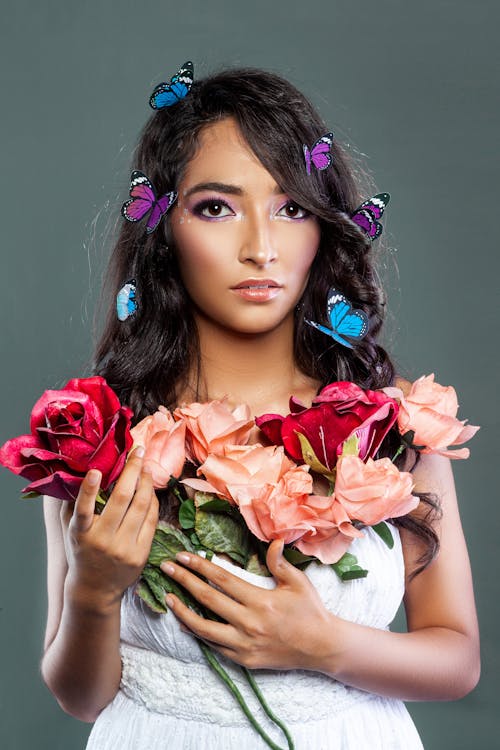 A Young Woman with Butterflies in her Hair Holding Flowers