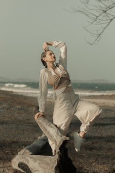 微风轻拂的海滩上，优雅的模特靠着浮木，穿着时尚的服装摆姿势