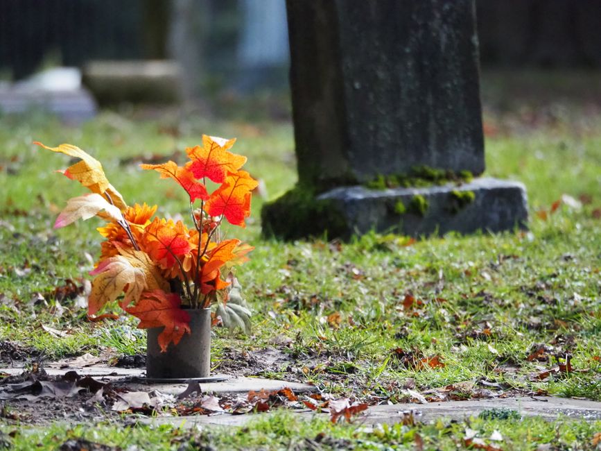 A colorful floral headstone saddle arrangement atop a granite tombstone A colorful floral headstone saddle arrangement atop a granite tombstone