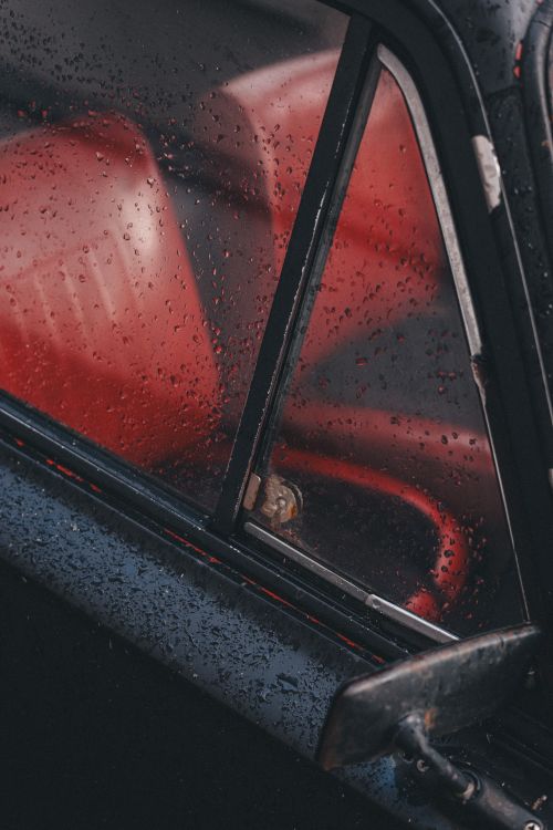 Free Close-up of raindrops on a vintage car's window, revealing a red leather interior. Moody and artistic vibe. Stock Photo