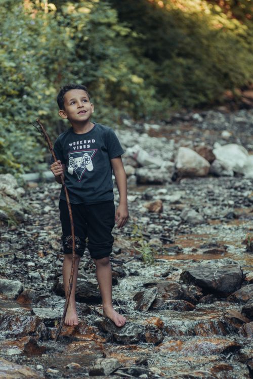 Young Boy Exploring Nature with Stick by Creek · Free Stock Photo