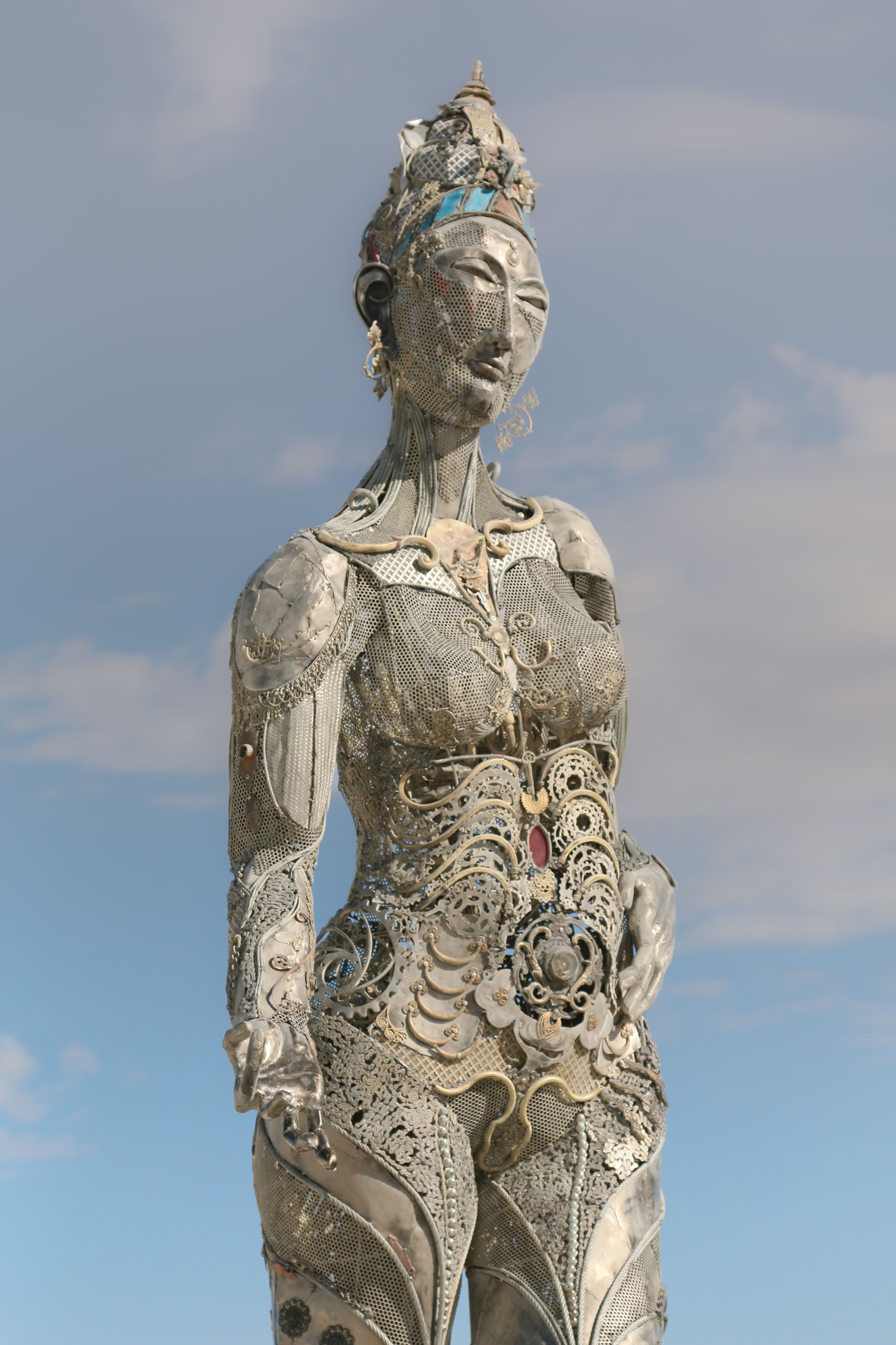 A detailed metal sculpture with ornate designs set outside against a clear sky.