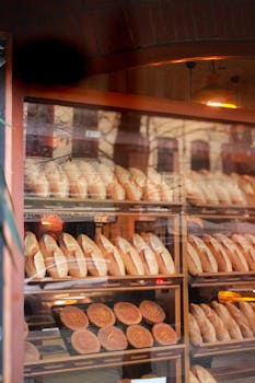 Warm bread loaves displayed in a bakery window, reflecting cozy ambiance.