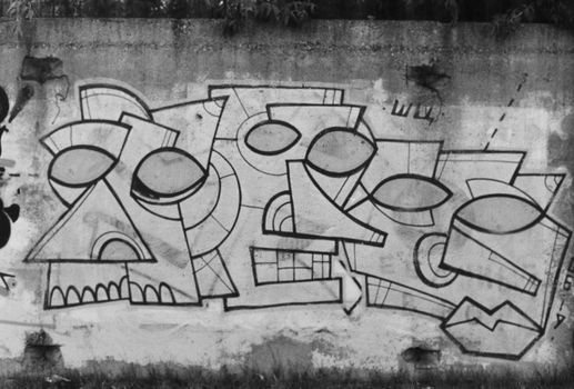 Black and white abstract mural on an urban concrete wall, featuring geometric shapes.