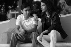 Black and white portrait of a stylish young couple sitting outdoors on a bench.