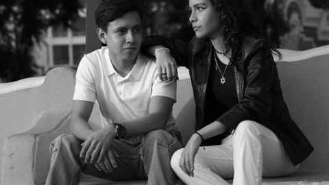 Black and white portrait of a stylish young couple sitting outdoors on a bench.