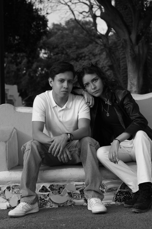 Free Stylish young duo posing outdoors on a bench in black and white. Stock Photo