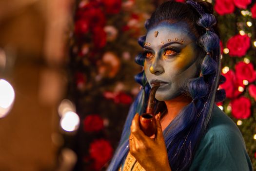 A vibrant artistic cosplay featuring detailed blue makeup and colorful costumes, inspired by fantasy themes.