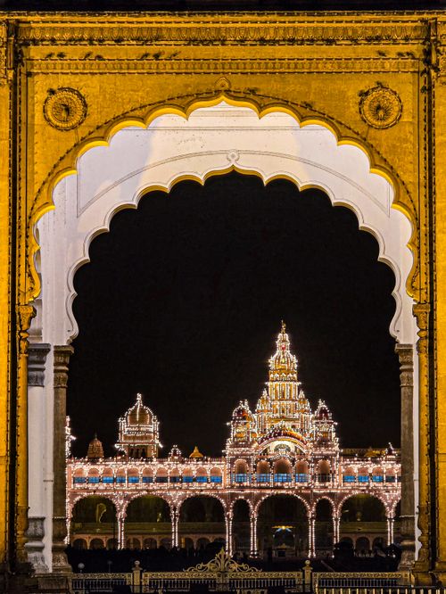 Free Stunning night view of Mysore Palace framed by an ornate archway, lit up beautifully. Stock Photo