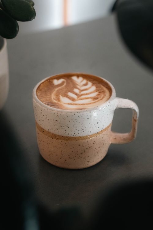 Free Close-up of a beautifully crafted latte with intricate art served in a rustic ceramic mug. Stock Photo