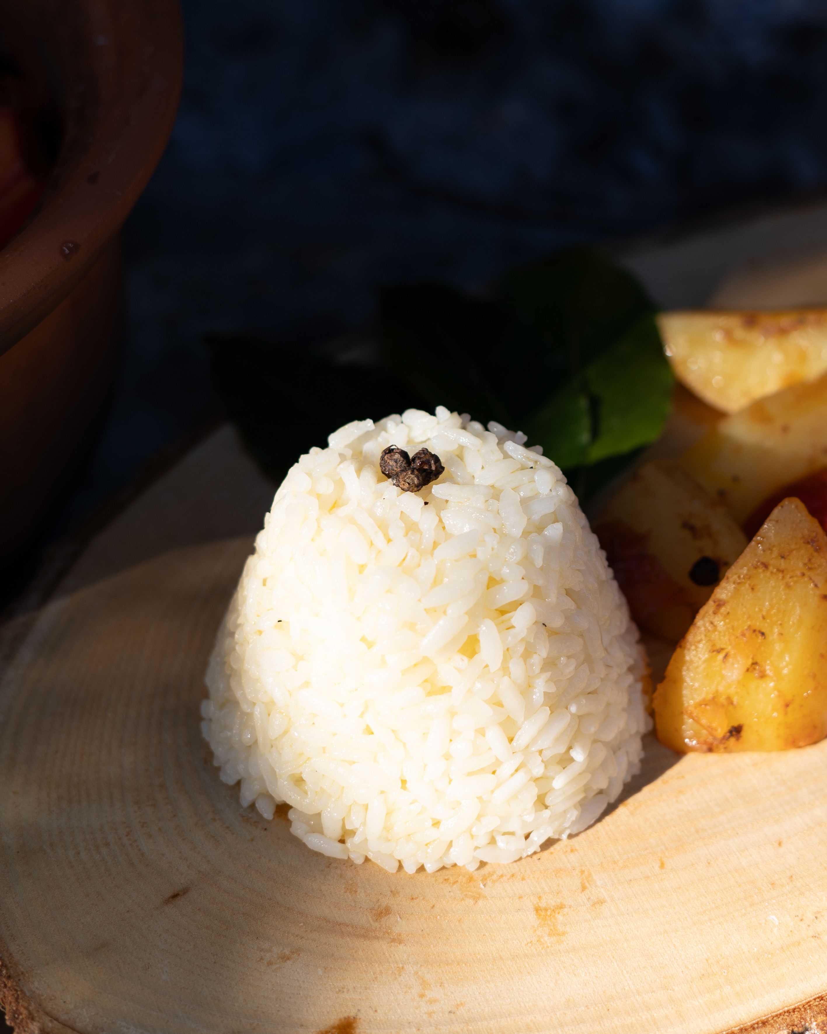 Appetizing rice and potato dish beautifully arranged on a wooden platter under natural light.
