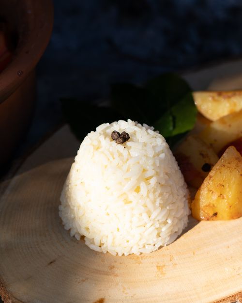 Free Appetizing rice and potato dish beautifully arranged on a wooden platter under natural light. Stock Photo