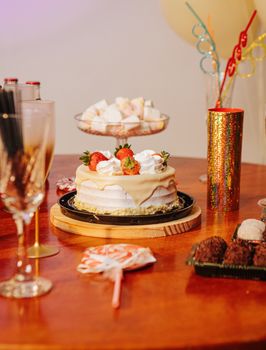 Festive table with a strawberry cake and assorted party treats, ready for celebration.