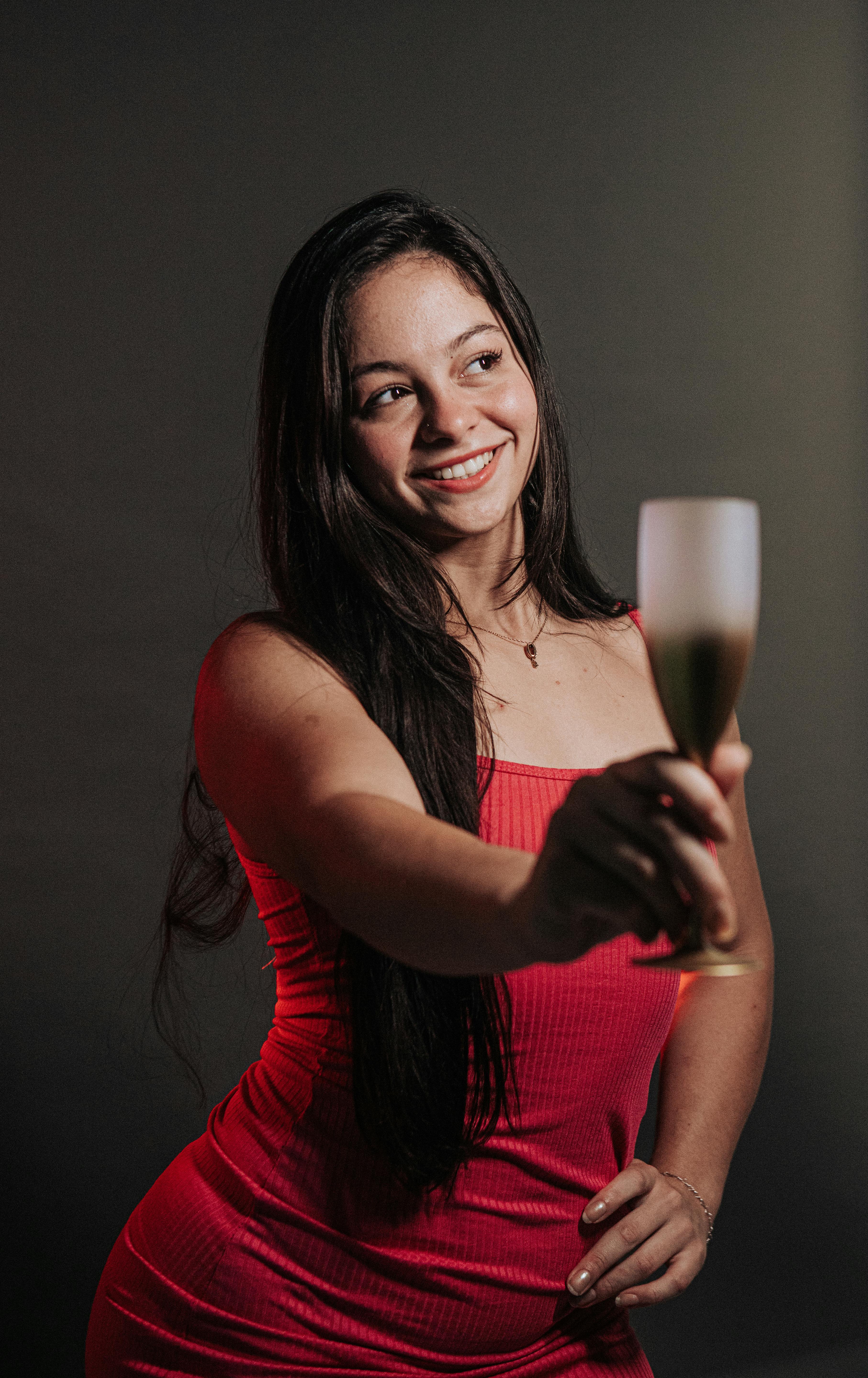 Young woman in red dress toasting with champagne at a party indoors.
