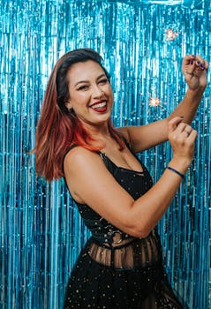 A cheerful woman enjoying a festive celebration with sparklers indoors.
