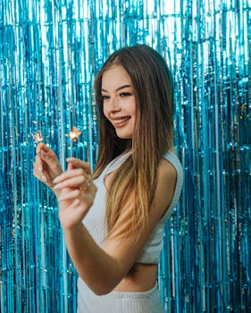 Joyful woman posing with sparklers against a festive blue backdrop.
