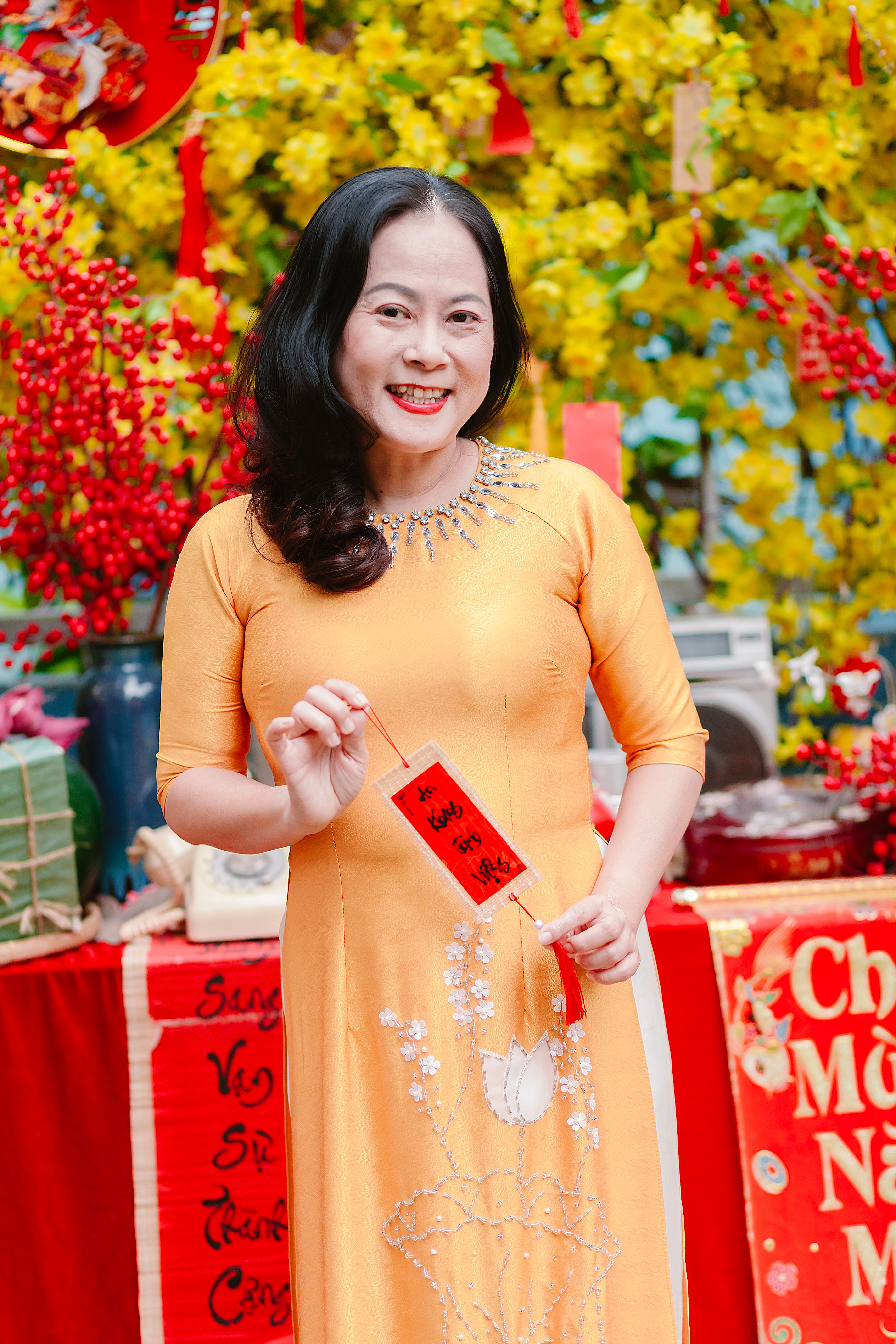 Woman in traditional dress holding a red envelope amidst Lunar New Year decorations.