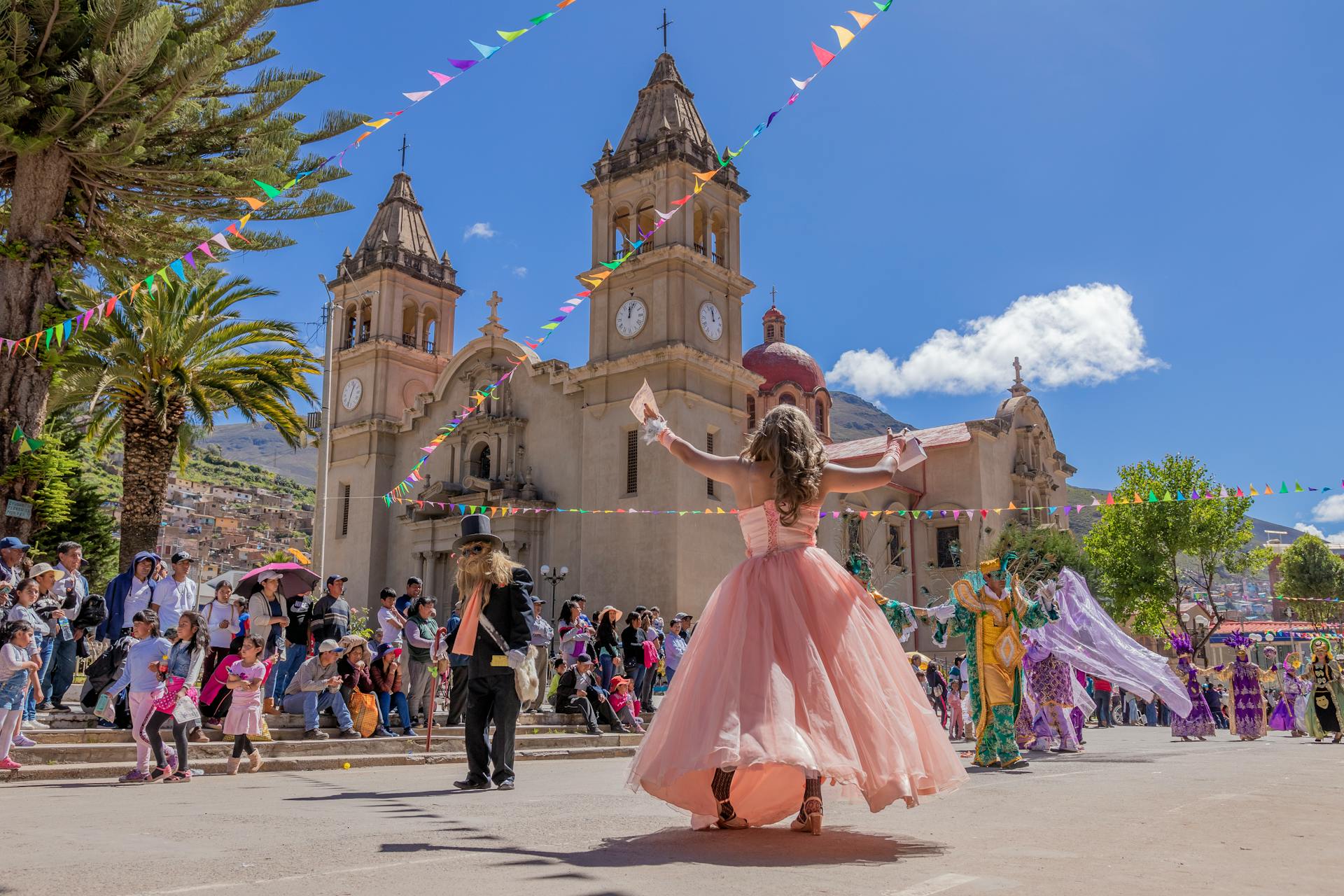 Colorful street festival with dancers and crowds near a historic church in Peru.