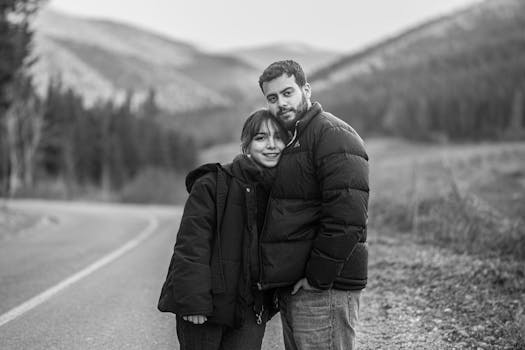 Portrait of a couple in a serene mountain landscape, black and white.
