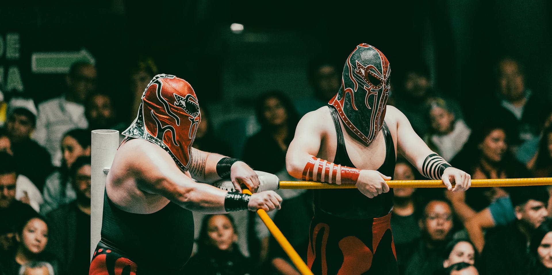 Masked wrestlers compete in an exciting Lucha Libre match before an engaged audience.