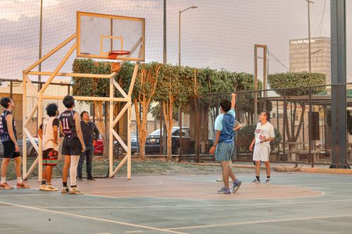 Free Players enjoy a lively street basketball game on an outdoor court at sunset. Stock Photo