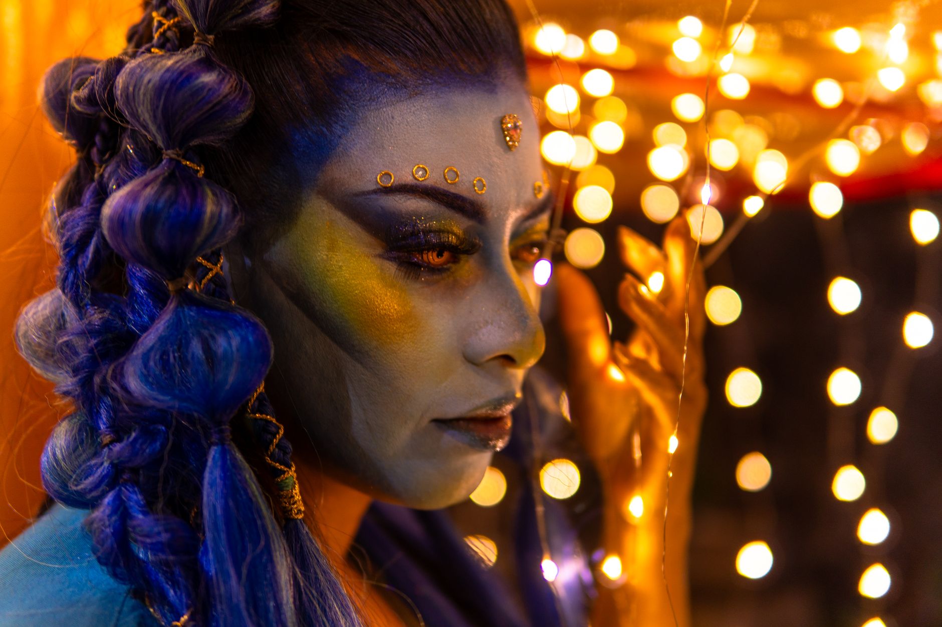 A vibrant portrait with artistic makeup and colorful bokeh lights.