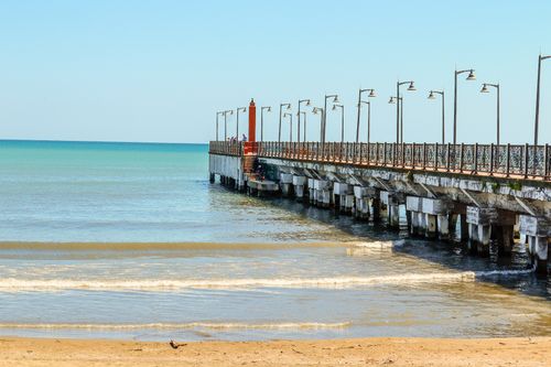 Free A tranquil scene of a pier stretching into the blue ocean with clear skies and gentle waves. Stock Photo