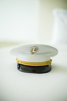 白色海军军官帽的特写，帽上带有金色徽章，置于白色表面