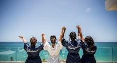 朋友们穿着长袍，欢乐的婚礼派对庆祝海滨景观，创造了难忘的婚前时刻