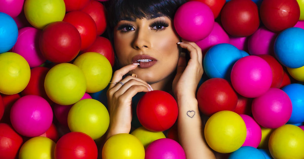A striking portrait of a woman surrounded by colorful balls, showcasing beauty and playful charm.