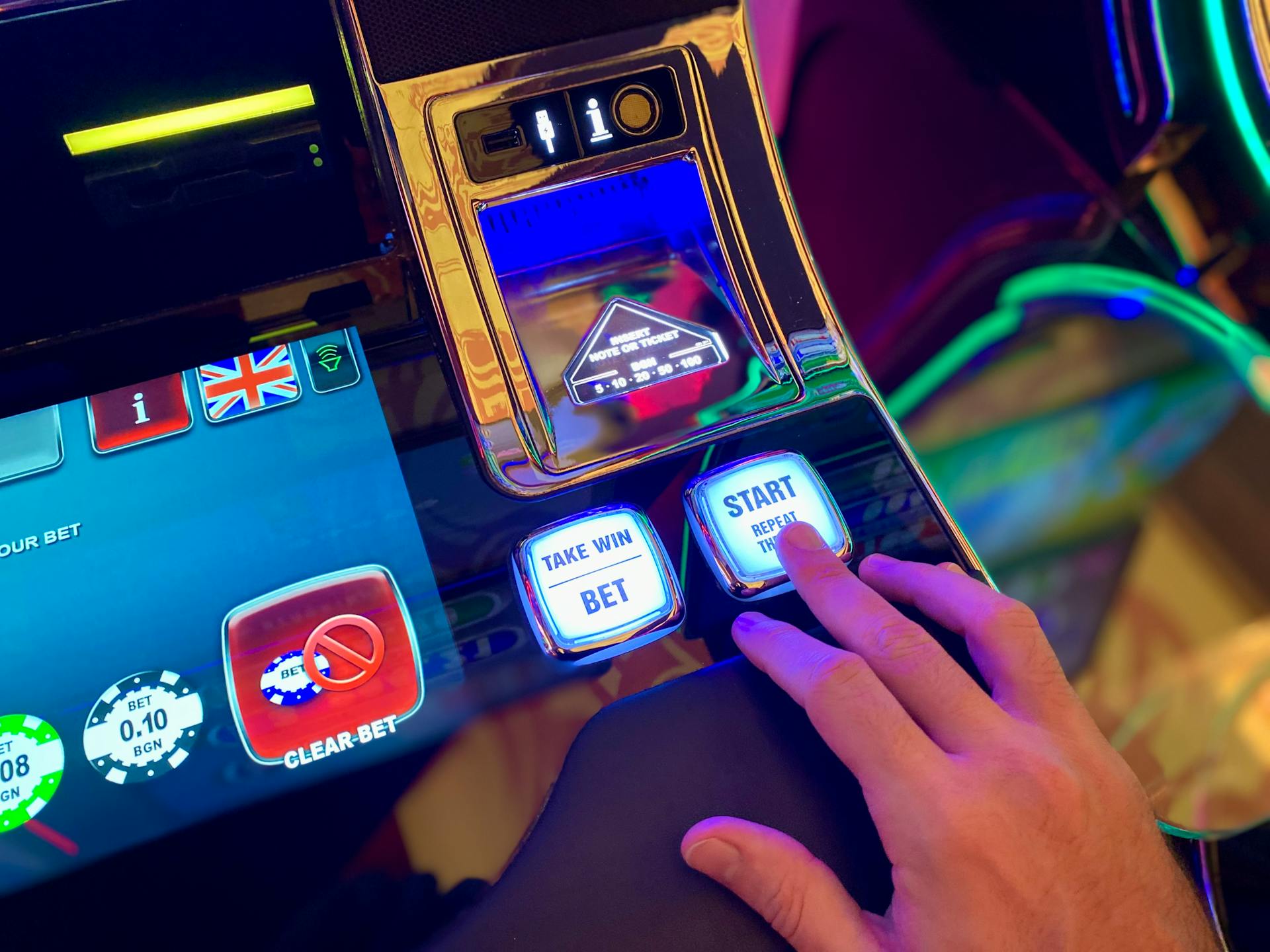 Hand interacting with buttons on a colorful casino slot machine interface.