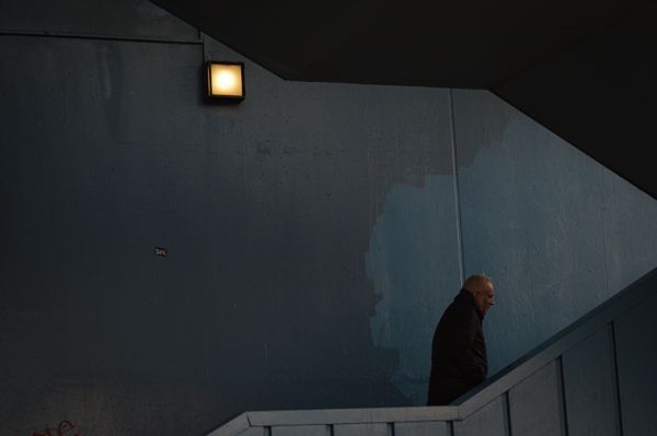 A man walking alone up a dimly lit urban stairwell — photo by Fatih Özer on Pexels