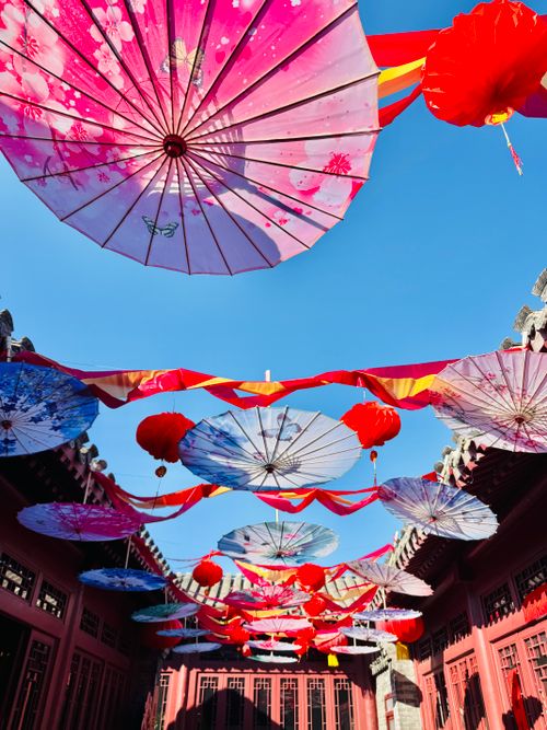 Free Vibrant umbrellas and lanterns hanging in a traditional Asian courtyard. Stock Photo