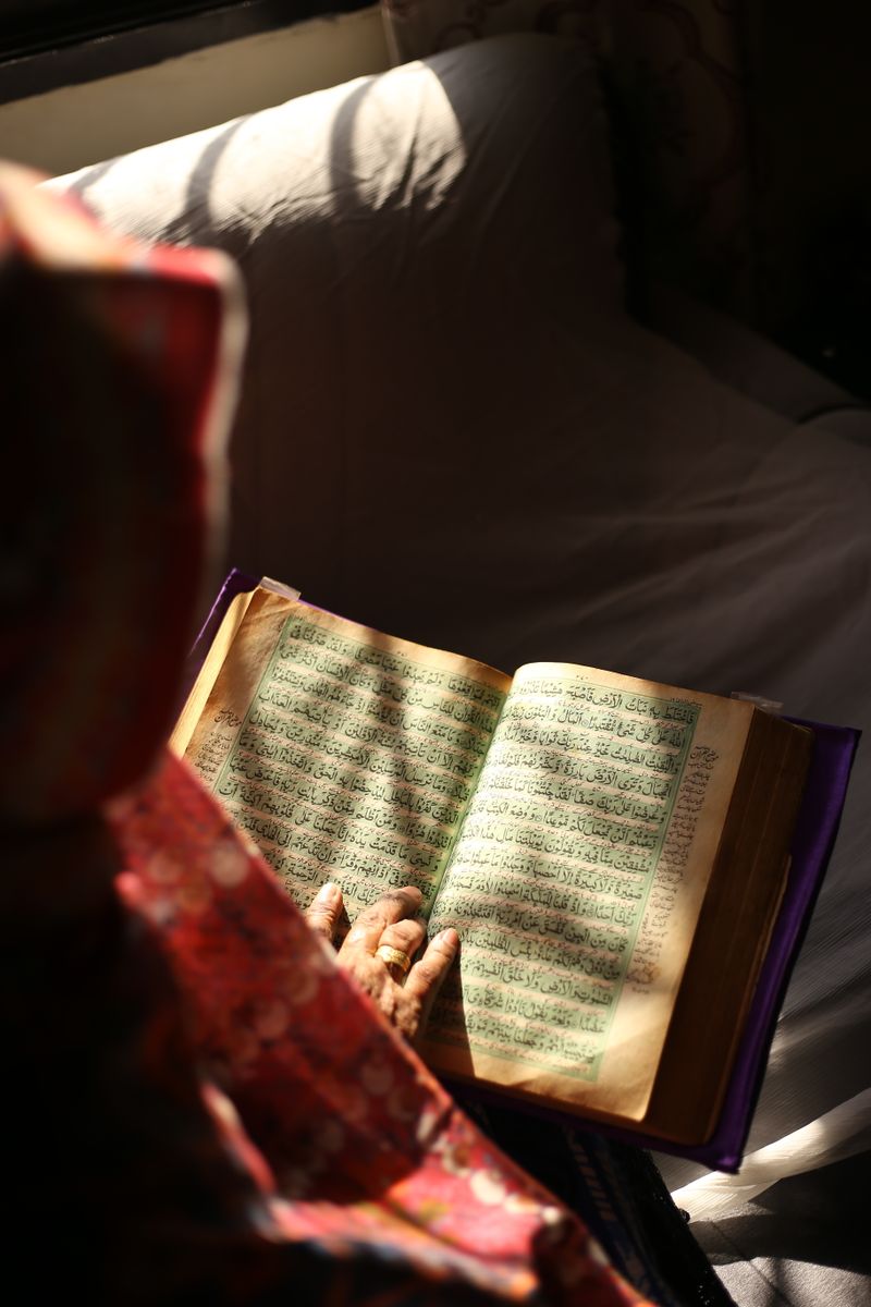 An adult student reading the Quran at home before her online class