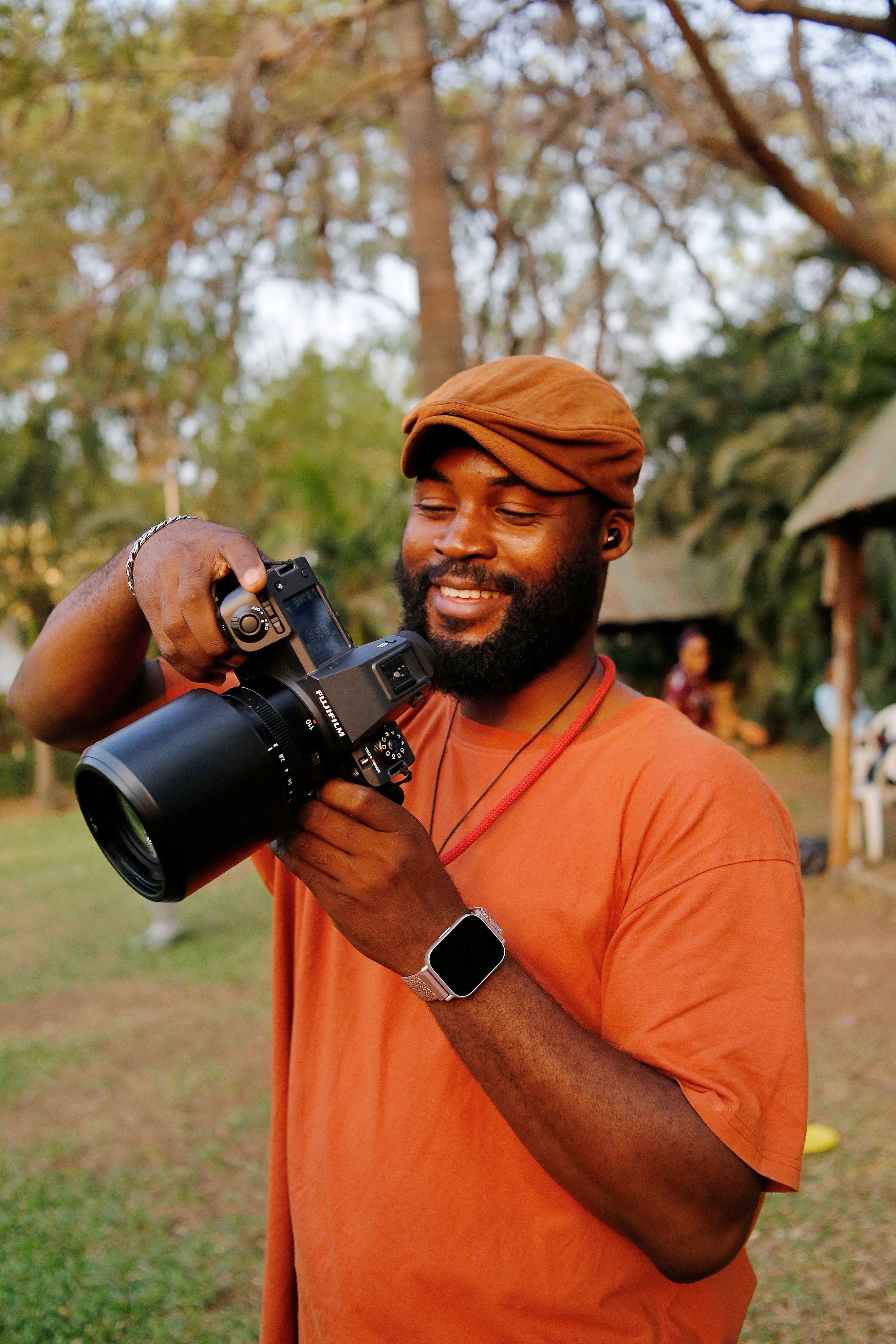 Smiling photographer using a camera outdoors in Abuja, Nigeria. Capturing lively moments.