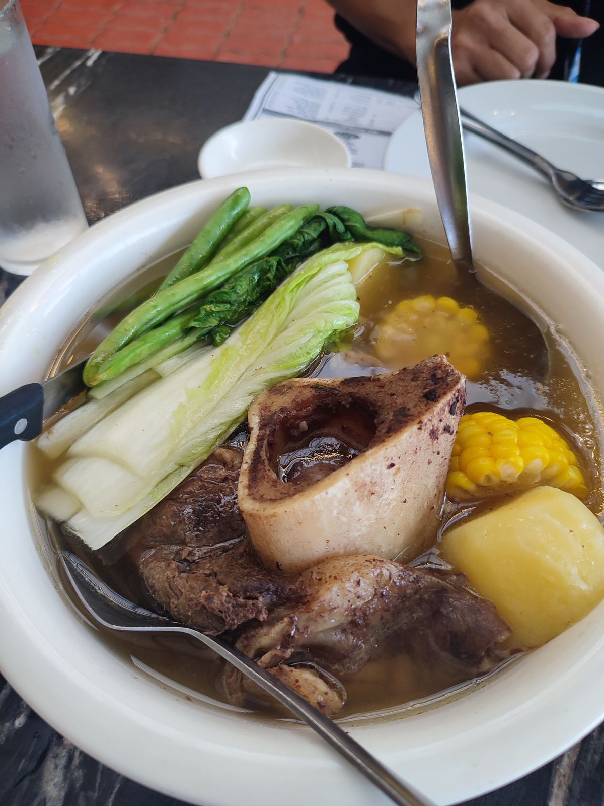 Bowl of beef bone broth with marrow bone and vegetables, showing the collagen-rich cuts used in traditional bone broth