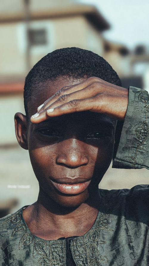 Free Portrait of a young person shielding their eyes from bright sunlight outdoors. Stock Photo