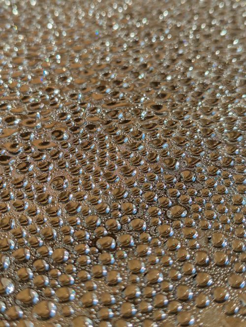 Free Macro image of sparkling dew drops creating a mesmerizing pattern on a golden background. Stock Photo
