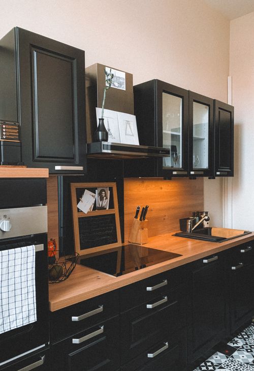 Free Sleek modern kitchen setup with black cabinets and wooden countertop. Stock Photo