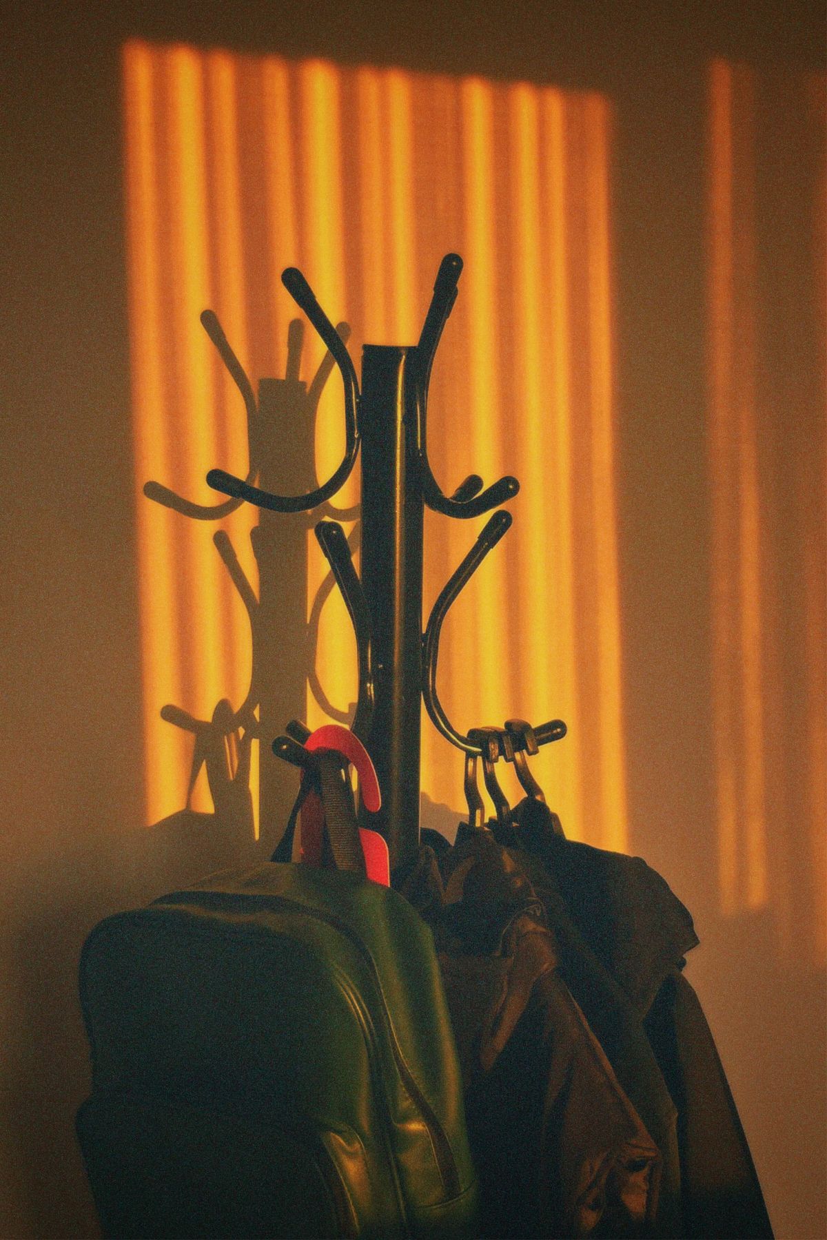 Coat rack with jackets and bags in warm evening light in a small apartment