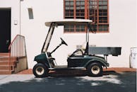 阳光明媚的日子里，一辆绿色的高尔夫球车静静地停在建筑物旁