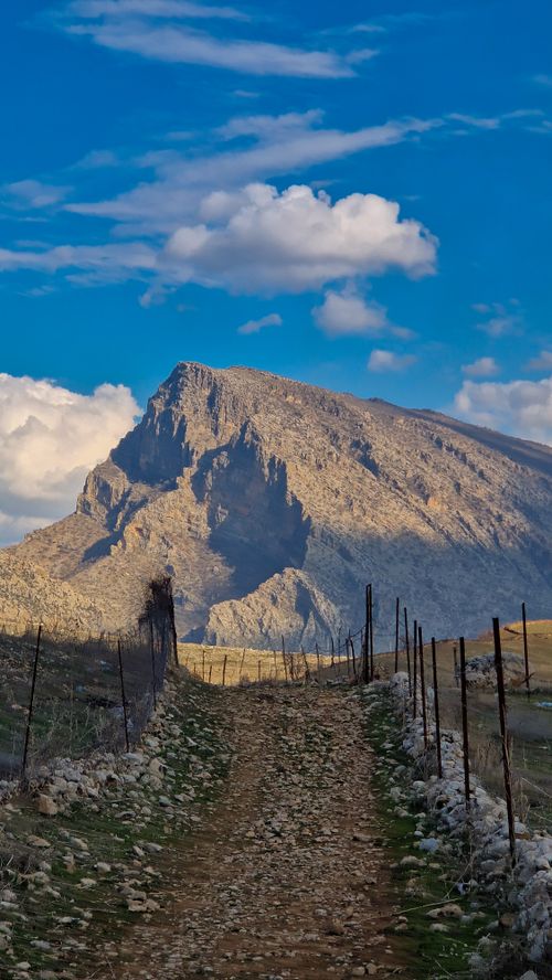 Free A rugged mountain path leading to a majestic mountain, under clear blue skies. Stock Photo