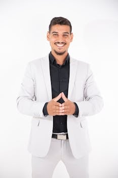 Smiling businessman in a light suit with hands clasped, showing confidence.