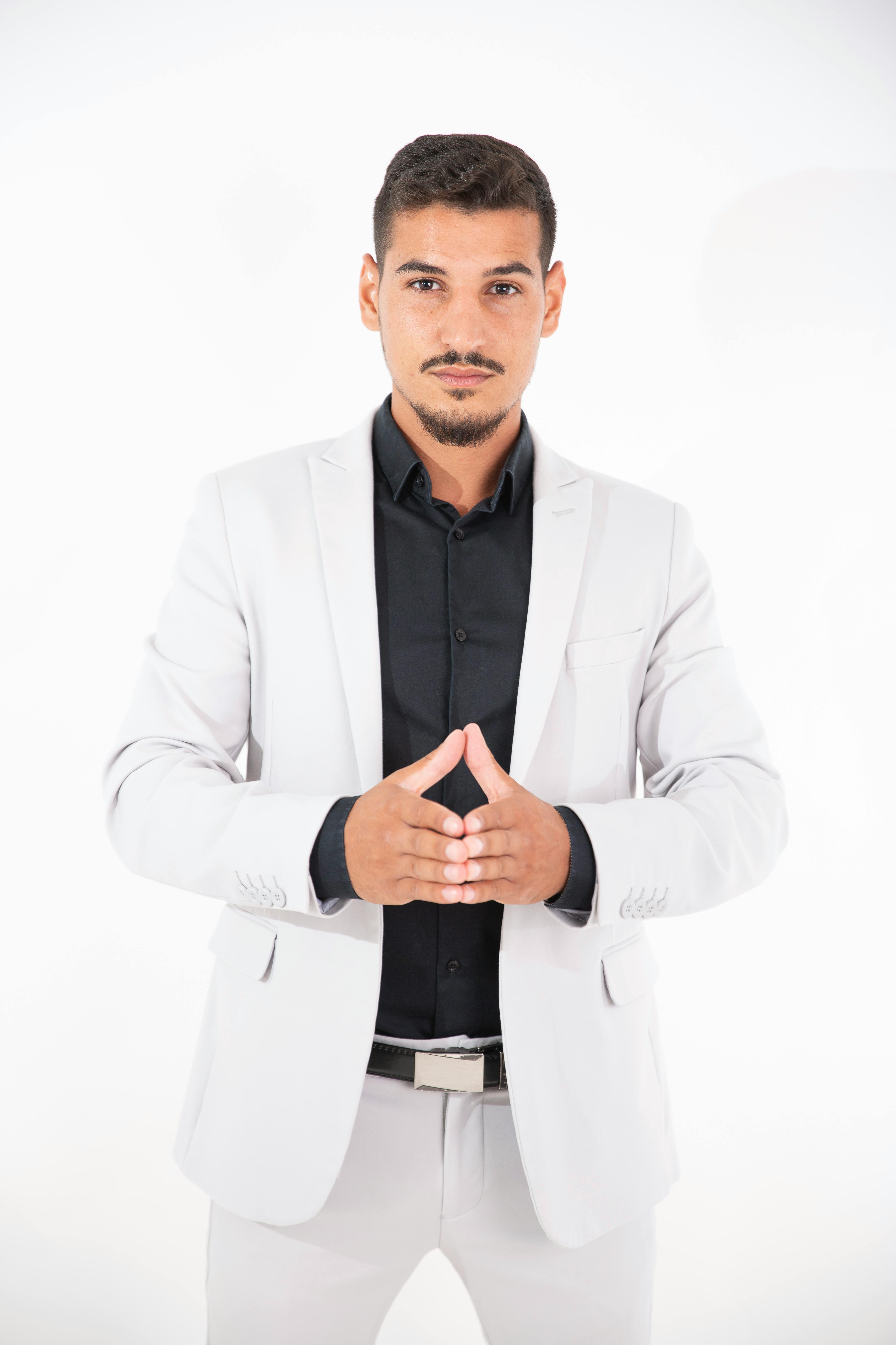Portrait of a confident young man in a white suit against a white background.