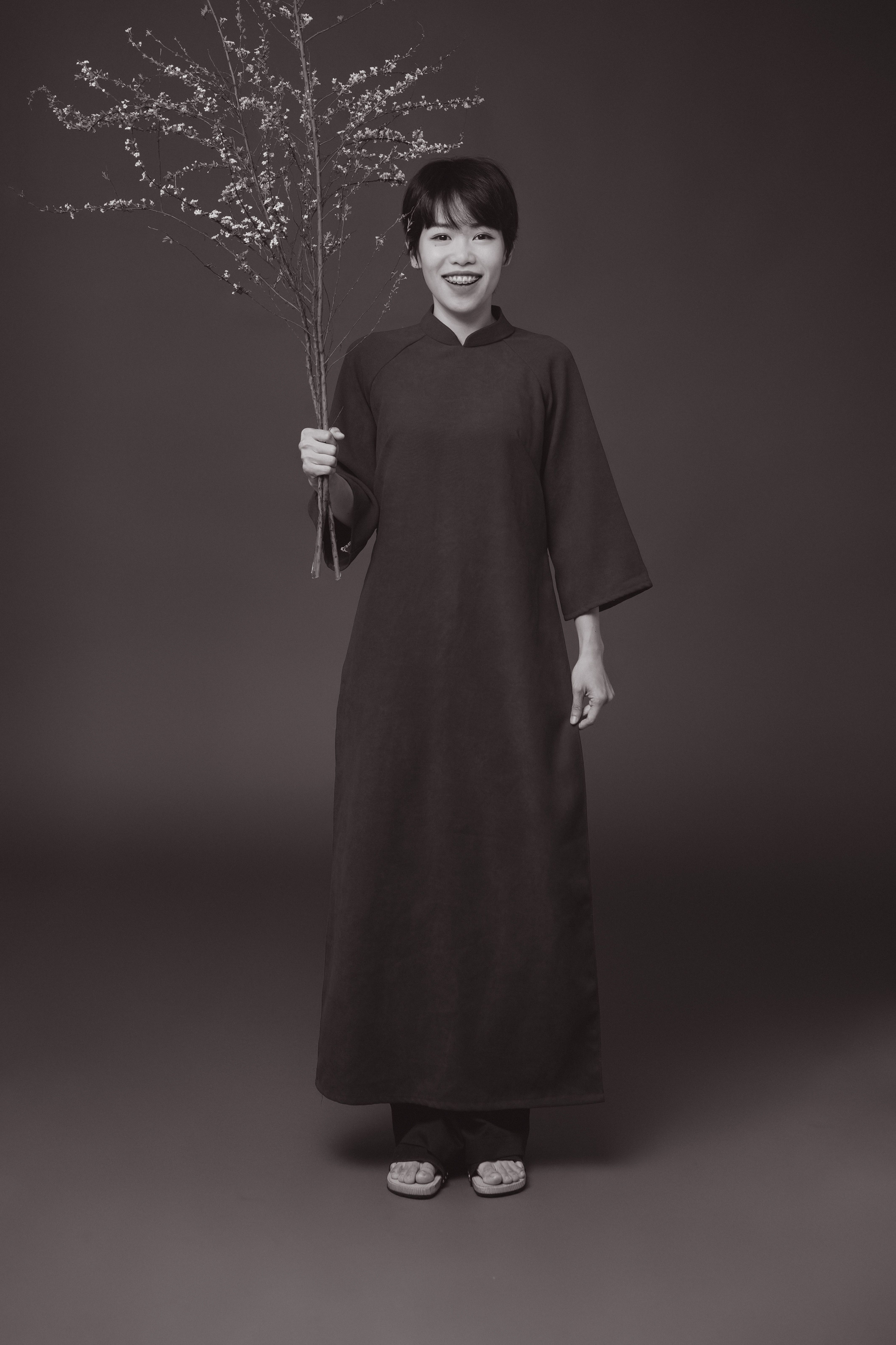 Black and white portrait of a woman in traditional dress holding flowers, showcasing elegance and simplicity.