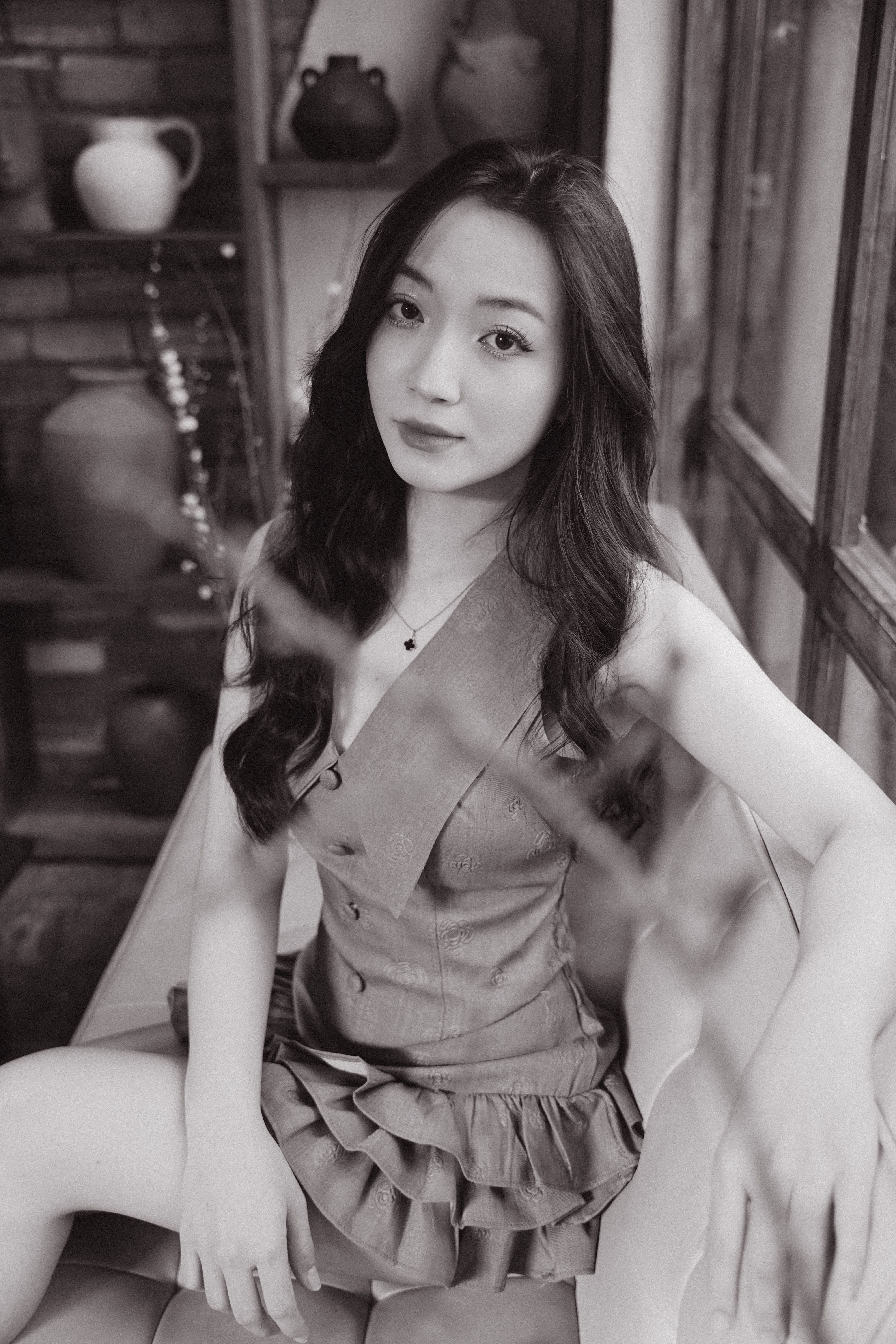 Black and white portrait of a woman sitting indoors, evoking classic elegance.