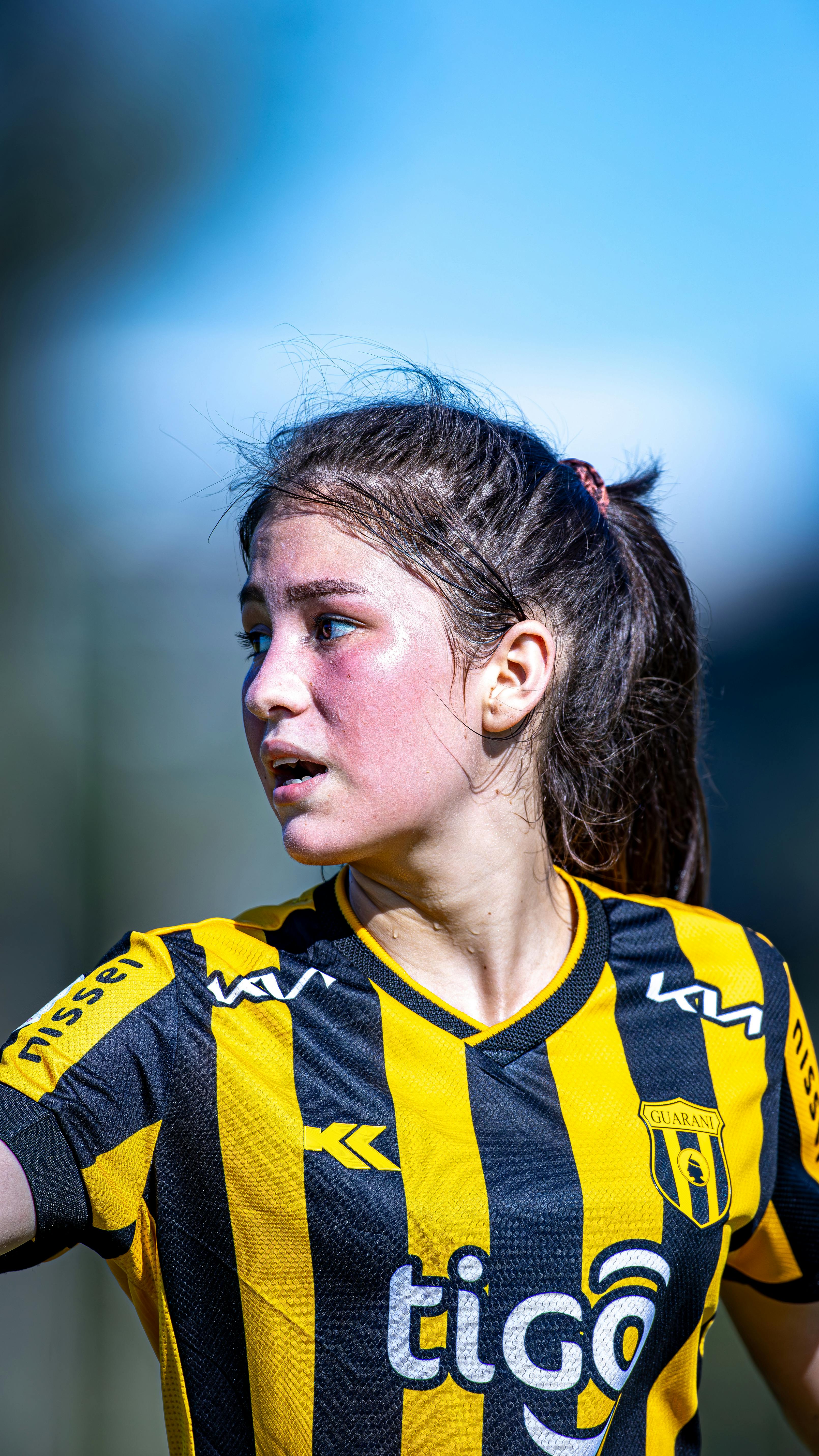 Portrait of a young female soccer player in action wearing black and yellow jersey.