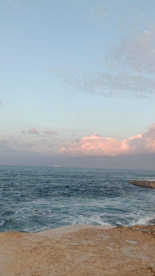 Free Calm ocean waves beneath a pastel sky during sunset, perfect for travel or nature themes. Stock Photo
