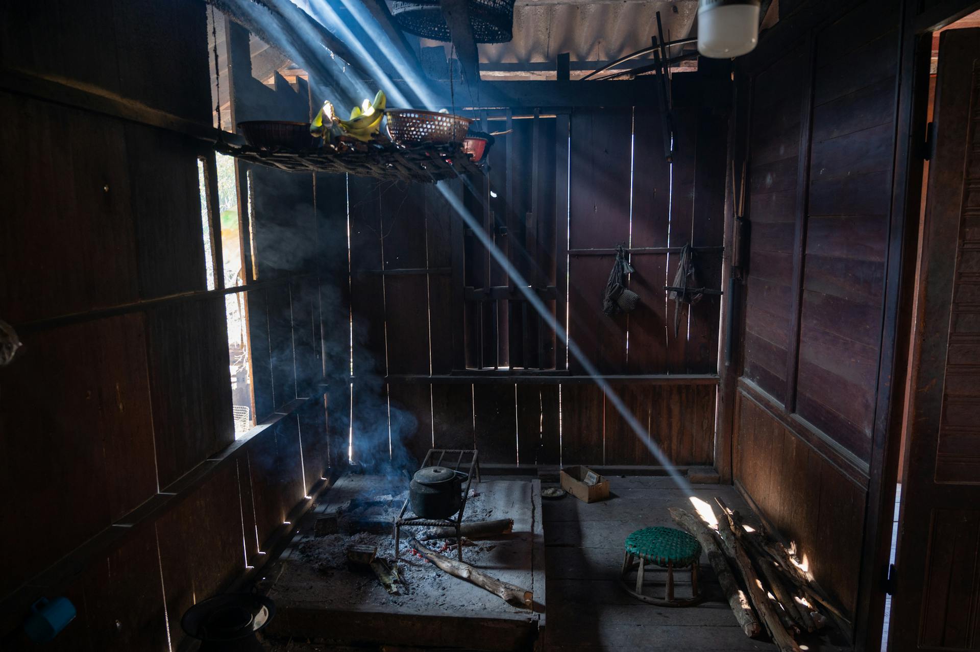 Cozy rustic kitchen with wooden walls, featuring sunlight beams shining through the smoke.