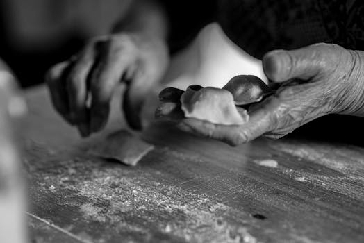 Close-up of an elder making handmade pasta, captured in monochrome.